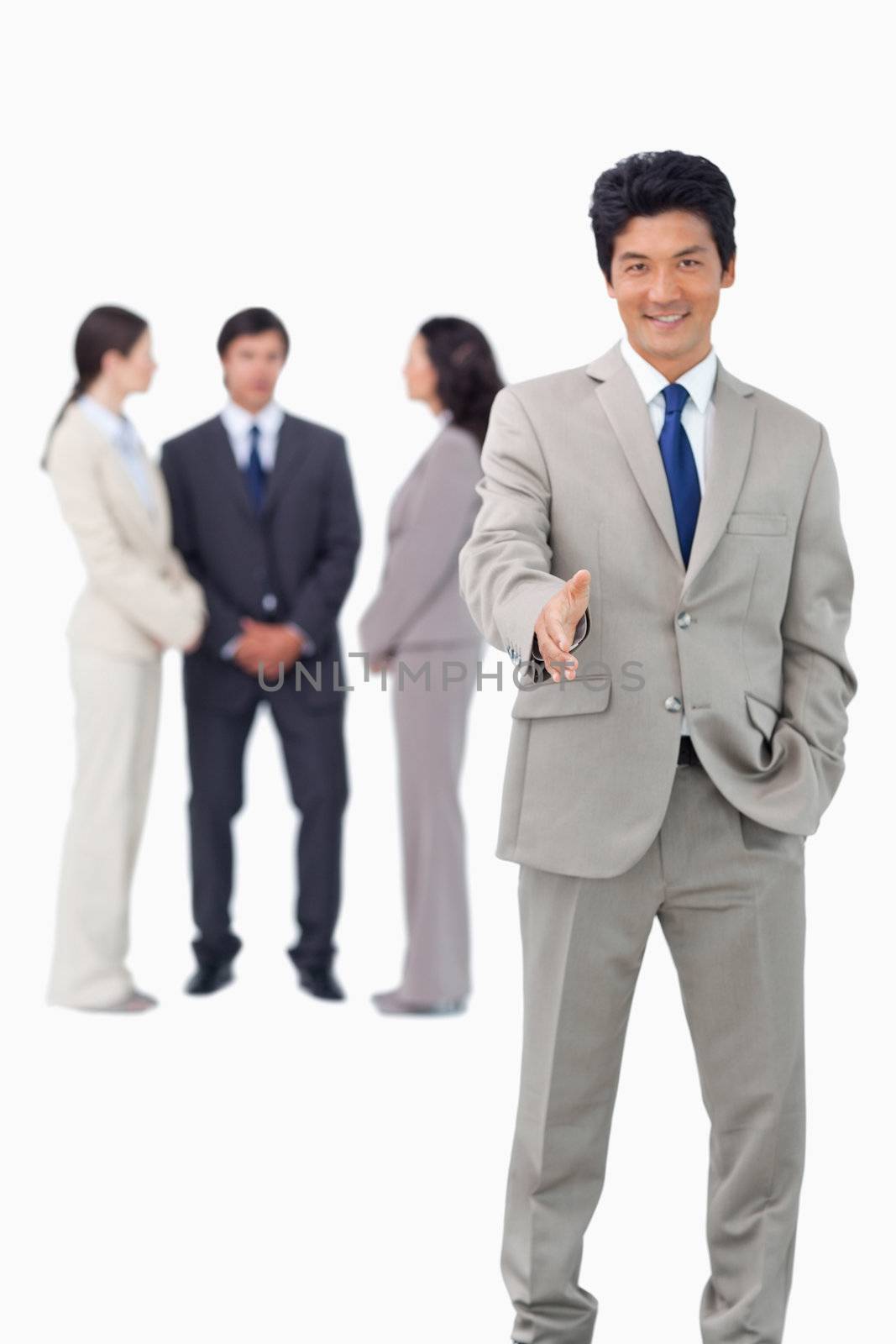 Salesman with team behind him offering hand against a white background