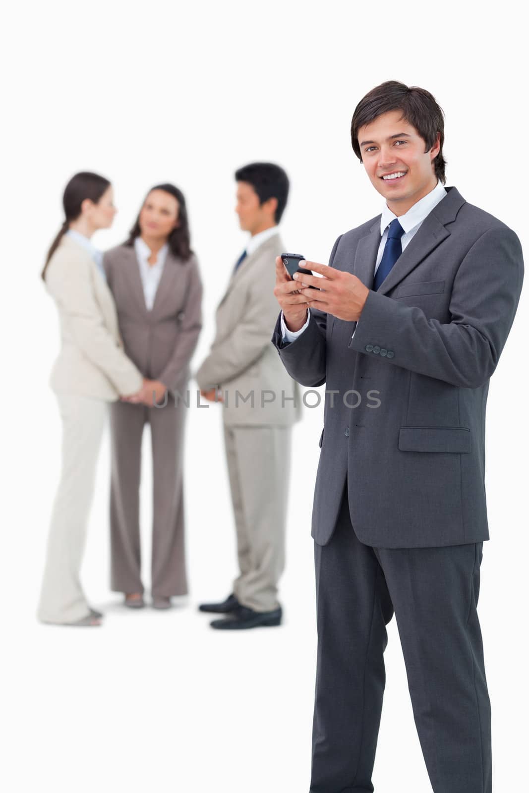 Smiling tradesman with cellphone and colleagues behind him against a white background