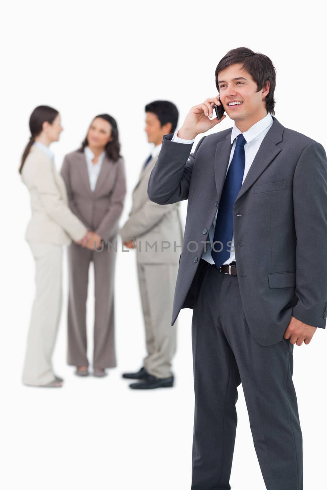 Smiling tradesman on cellphone with team behind him against a white background