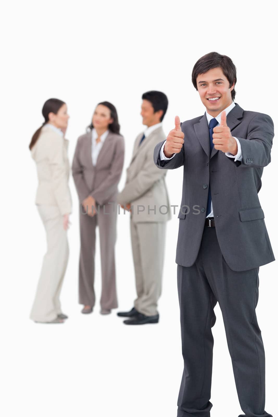 Salesman giving thumbs up with colleagues behind him against a white background