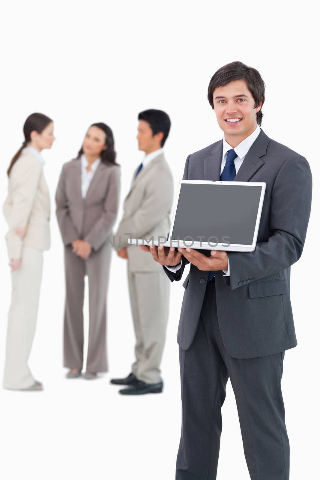 Smiling salesman showing laptop screen with team behind him against a white background