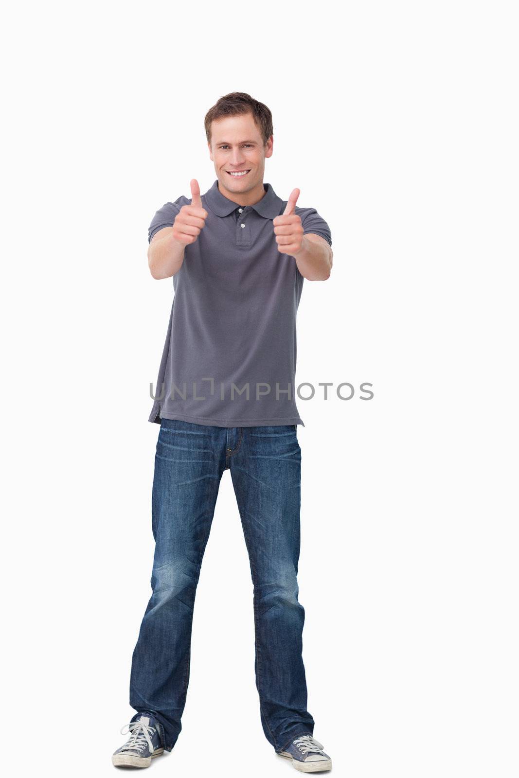 Smiling young man giving thumbs up against a white background