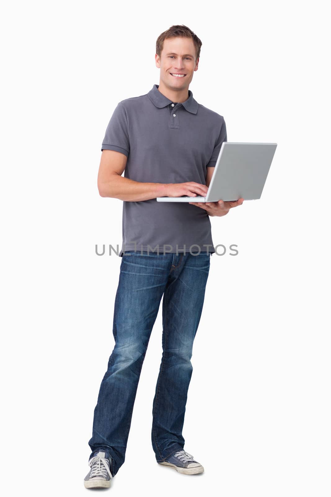Smiling young man working on his notebook against a white background