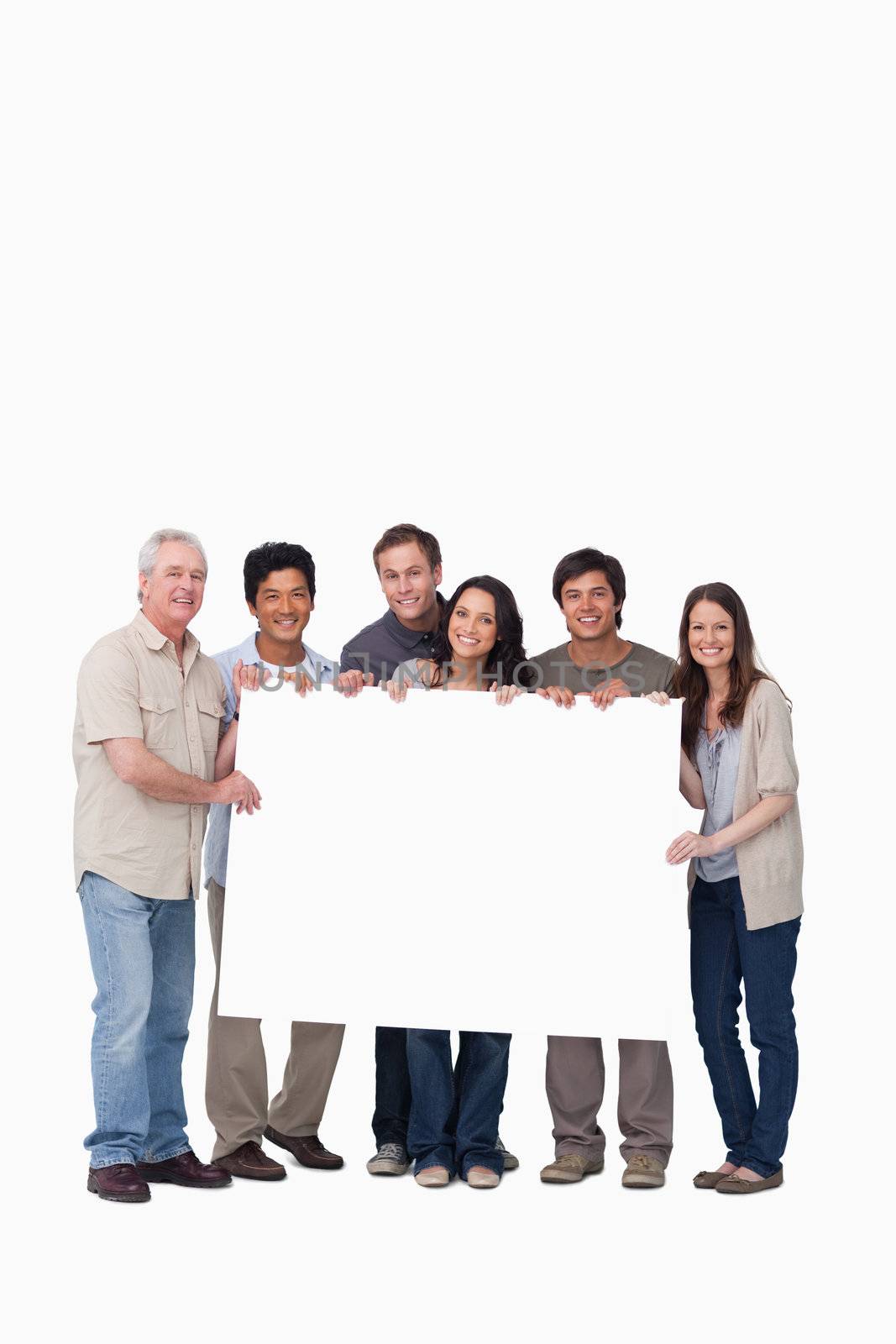 Smiling group of friends holding blank sign together against a white background