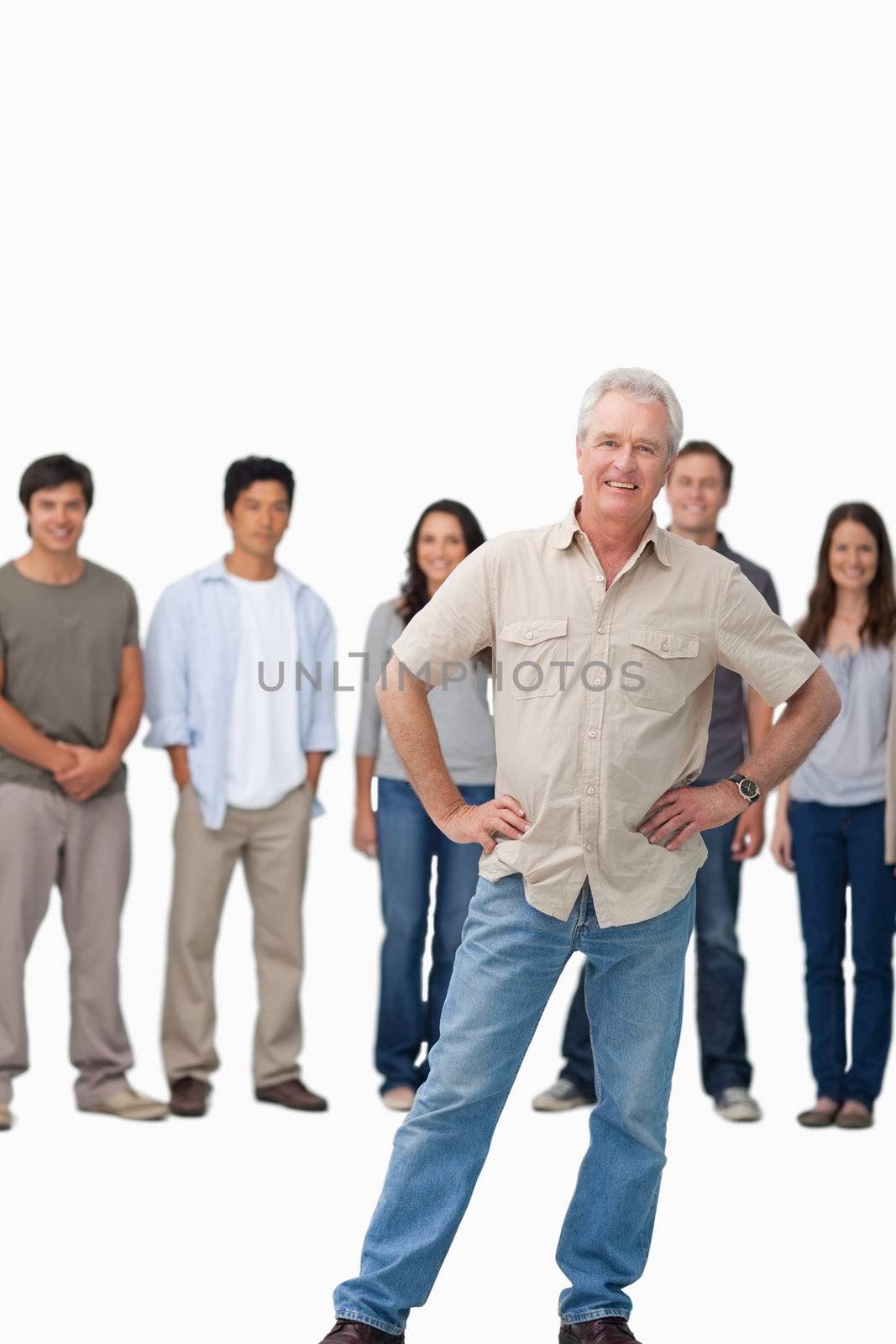 Mature man with hands on his hip and young people behind him against a white background