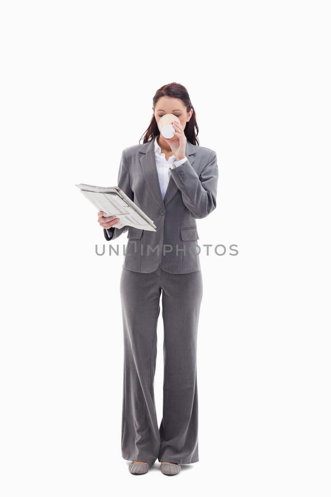 Businesswoman drinking a coffee and reading a newspaper against white background