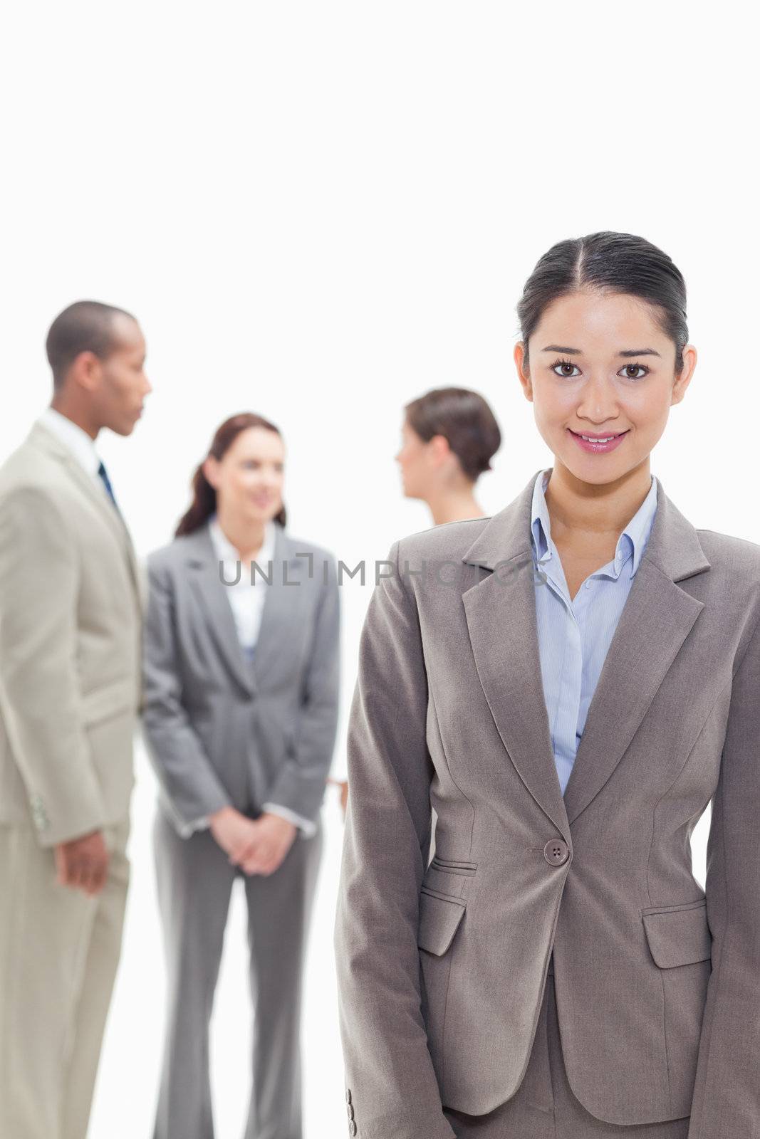 Businesswoman smiling with co-workers talking in the background against white background