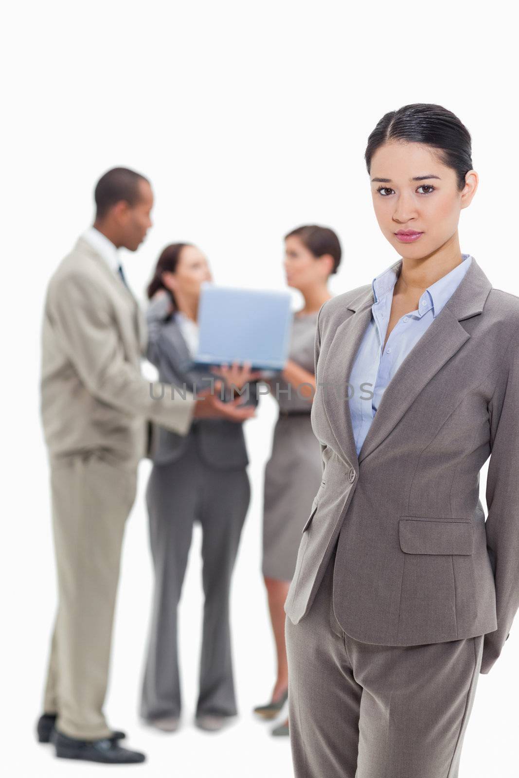 Serious businesswoman with co-workers talking with a laptop in the background