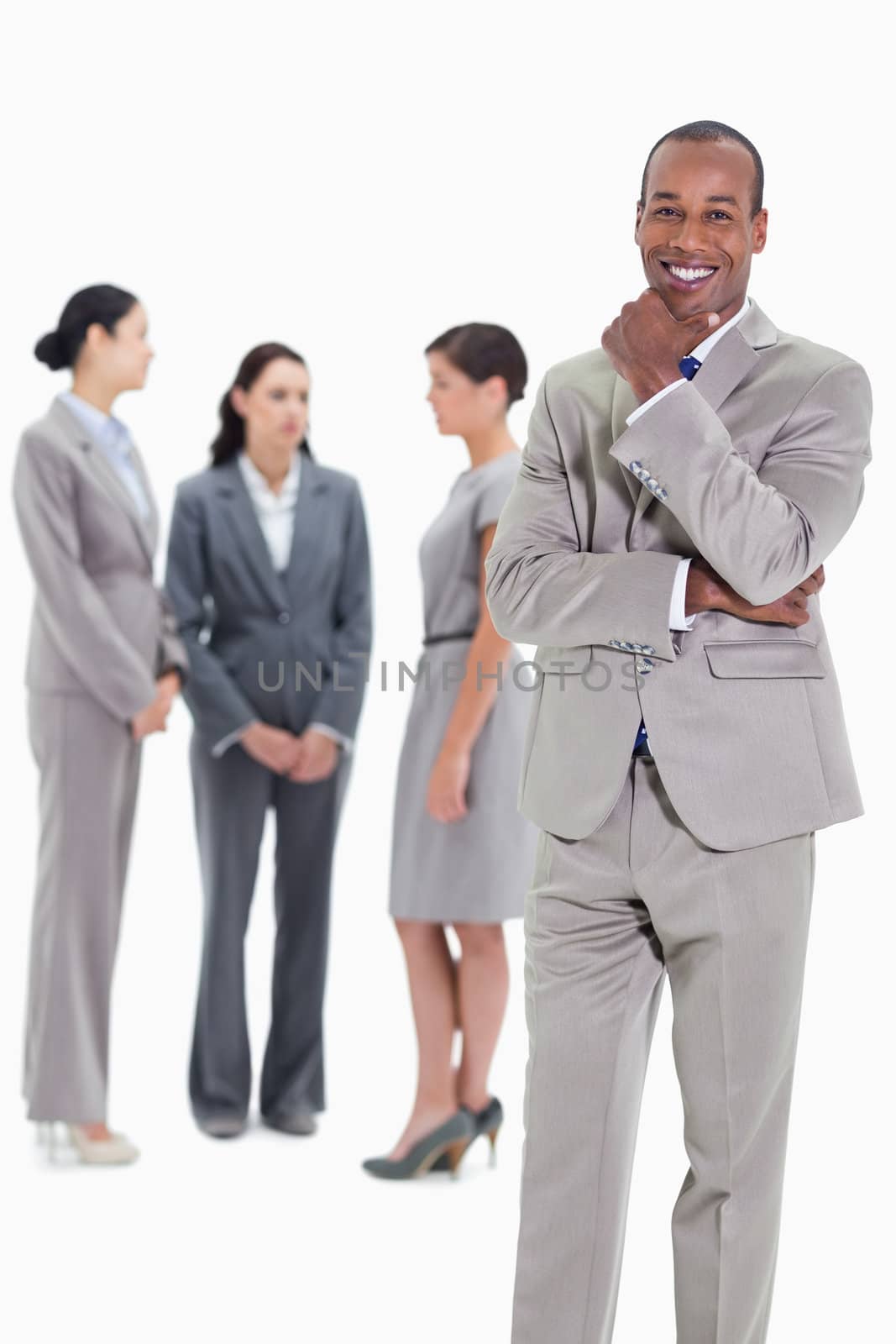 Happy businessman with a hand on his chin and three co-workers talking seriously in the background