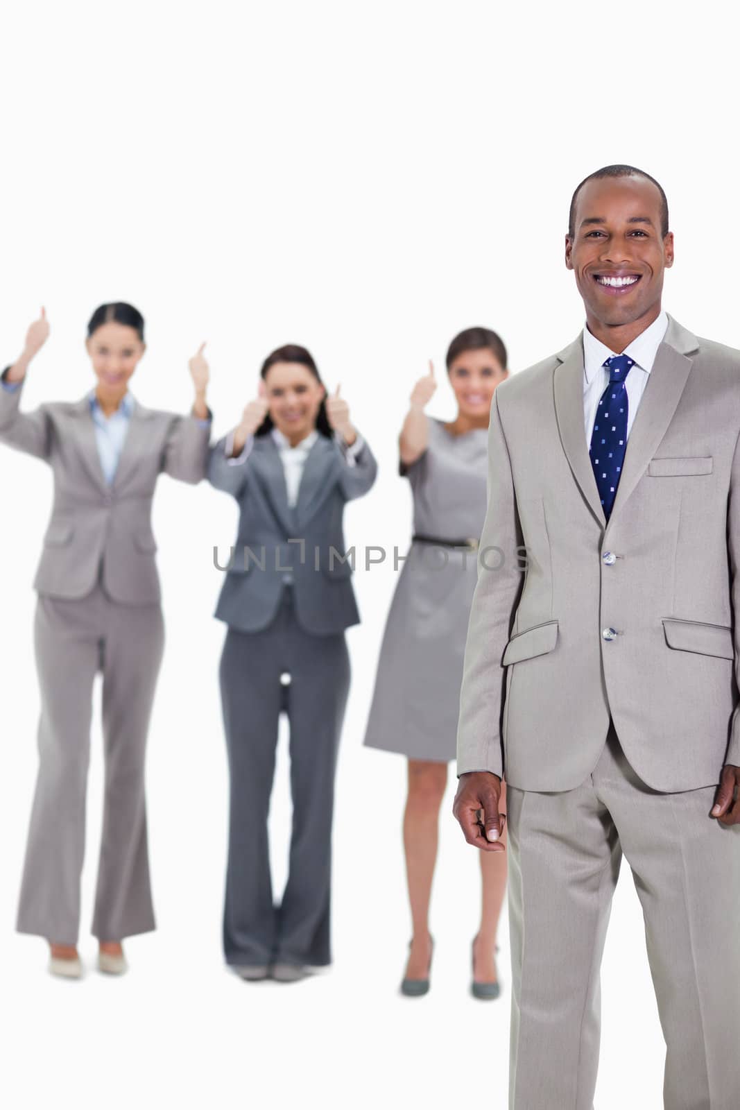 Happy businessman with three approving co-workers in background with thumbs up