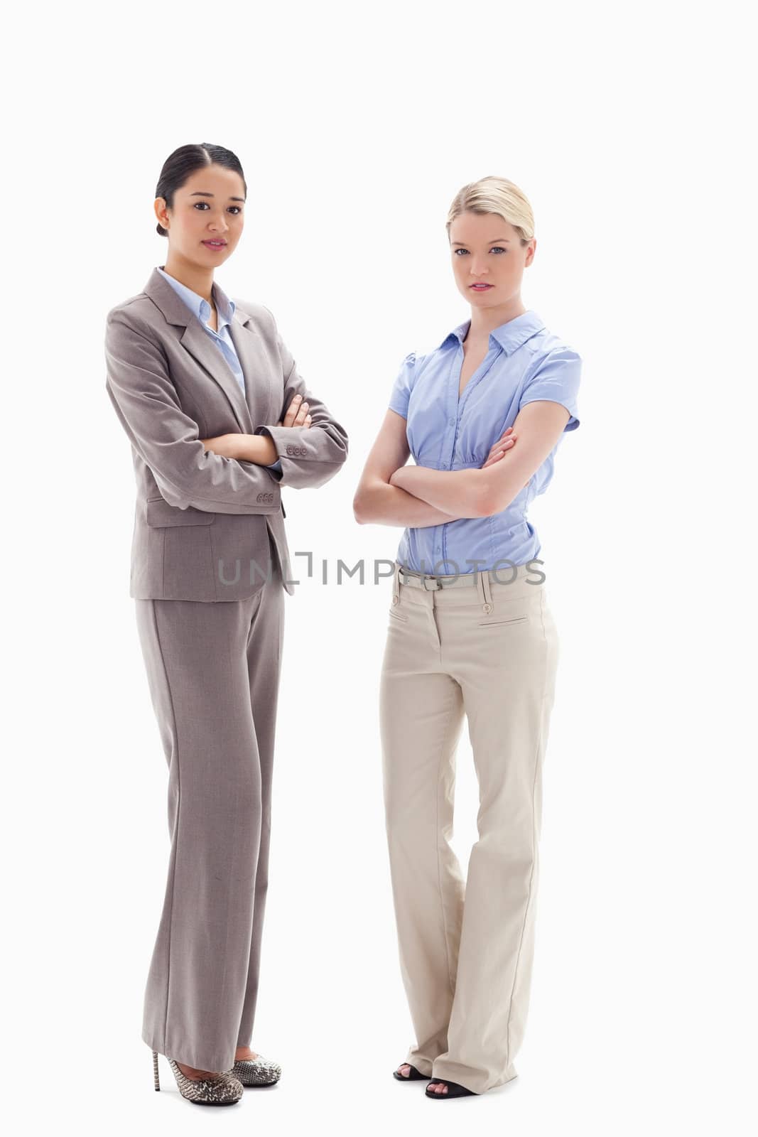 Two serious women crossing their arms against white background