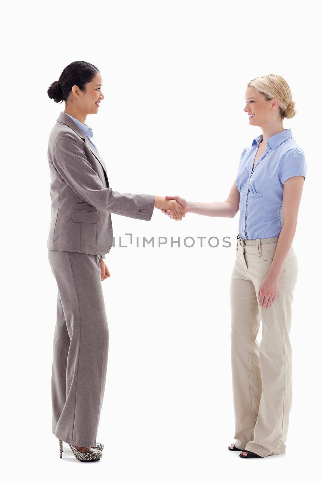 Women shaking hands happily against white background