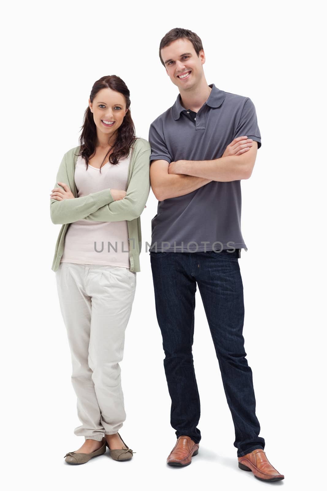 Smiling couple crossing their arms against white background