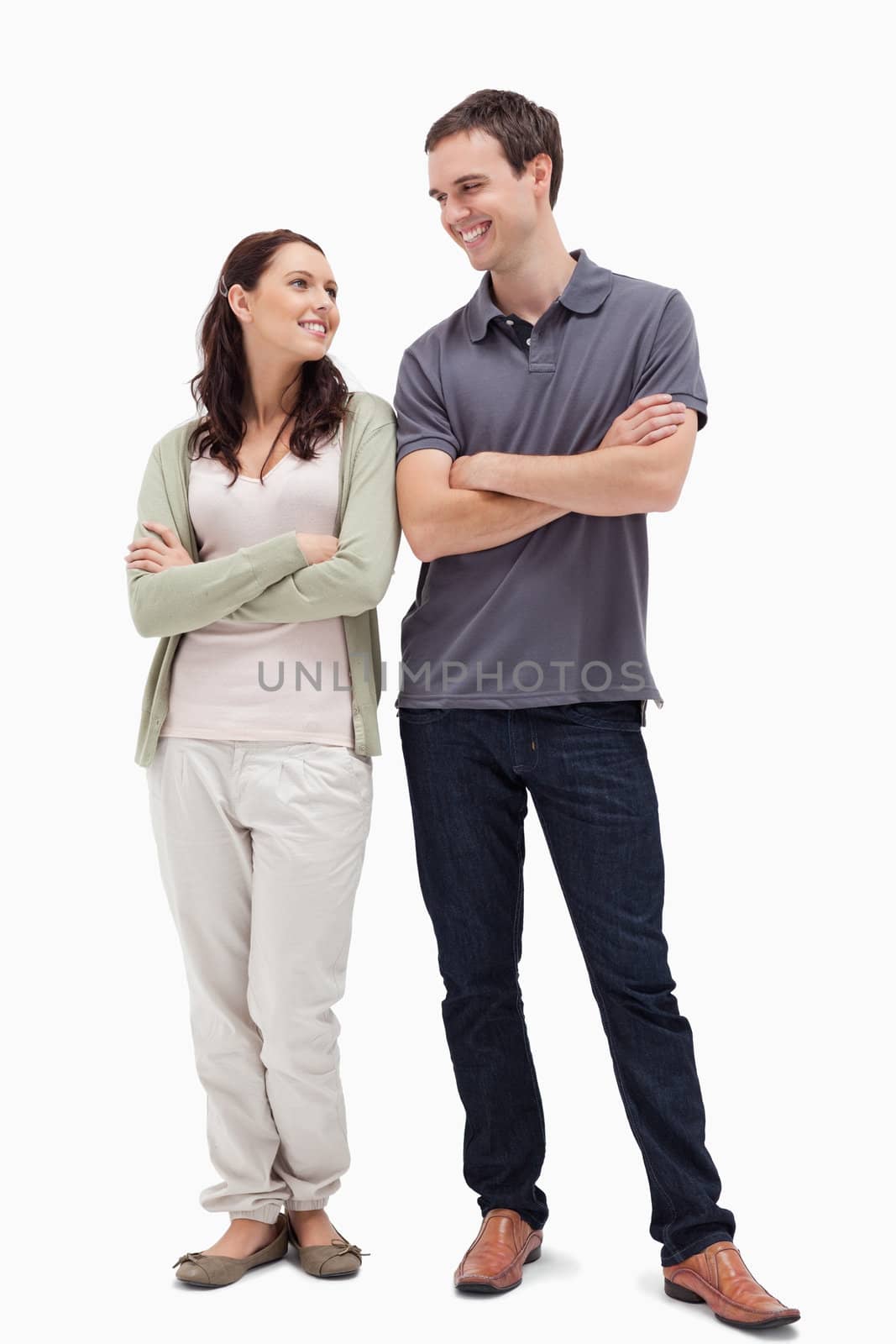 Couple with a complicit smile while crossing their arms against white background