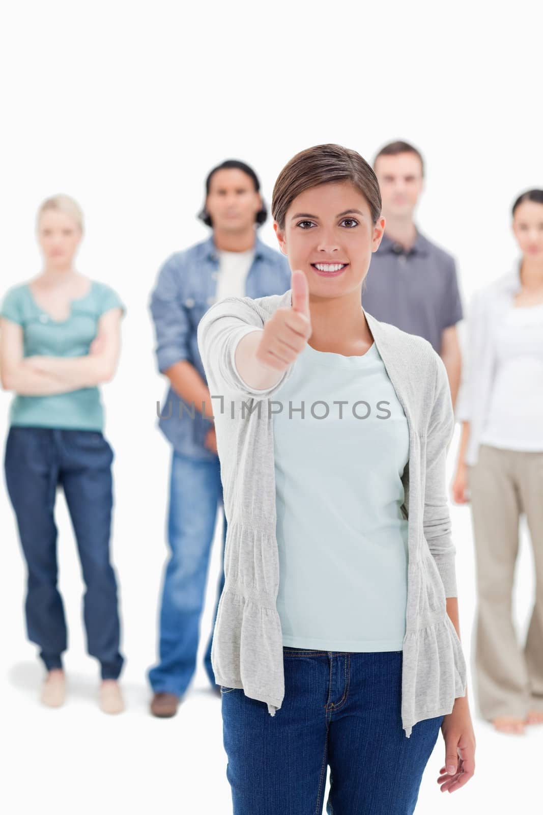 Close-up of a woman giving the thumb-up with people behind  by Wavebreakmedia