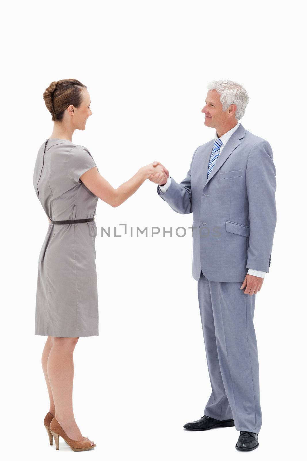 White hair businessman smiling face to face and shaking hands with a woman against white background