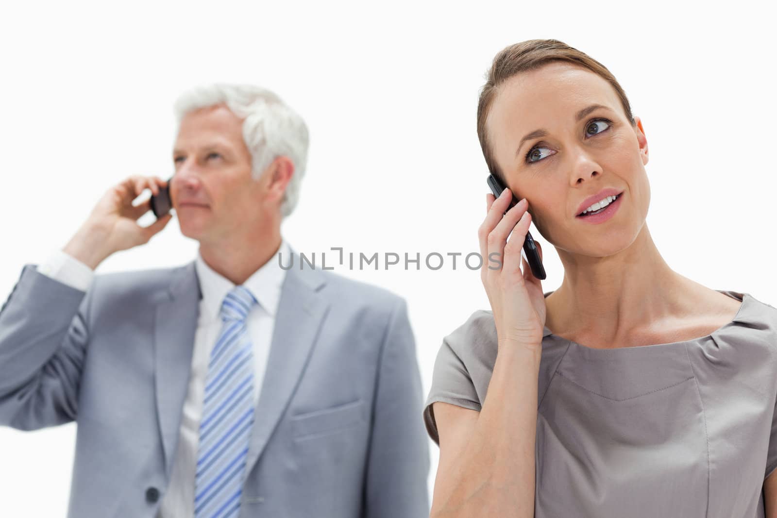 Close-up of a woman on the phone with a white hair businessman in background