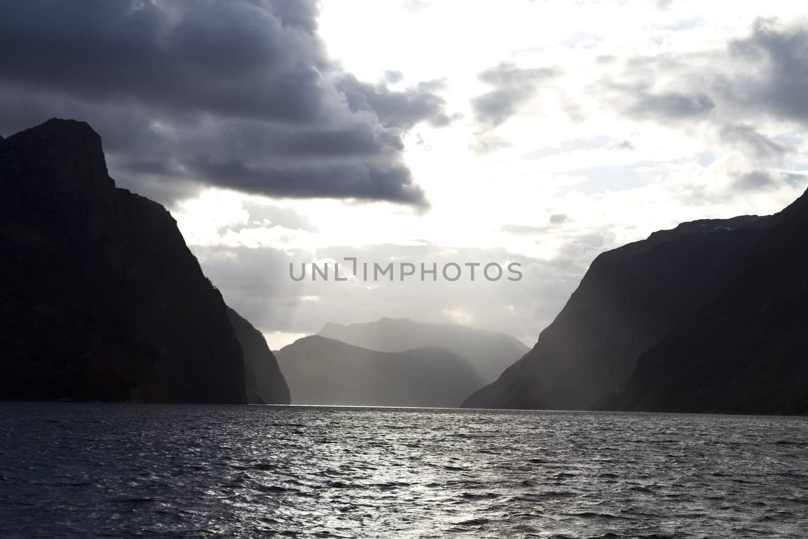 evening view over fjord in norway with cloudy sky and steep coast