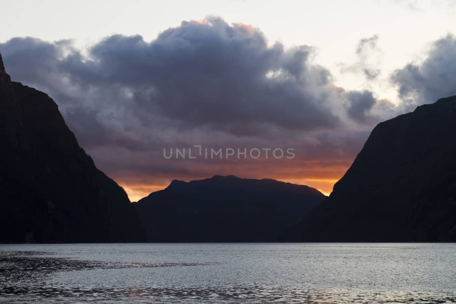 evening view over fjord in norway with cloudy sky and steep coast