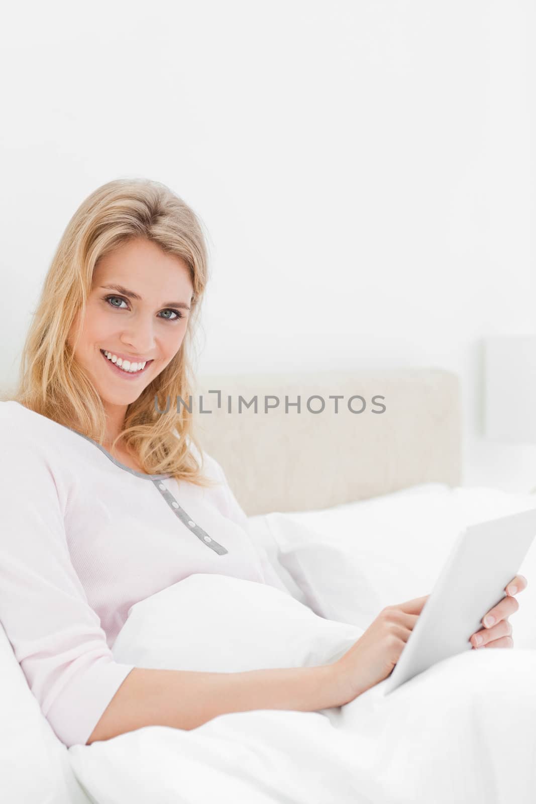 A close up shot of a smiling woman who is using a tablet pc as she is looking up and a bit to the side.