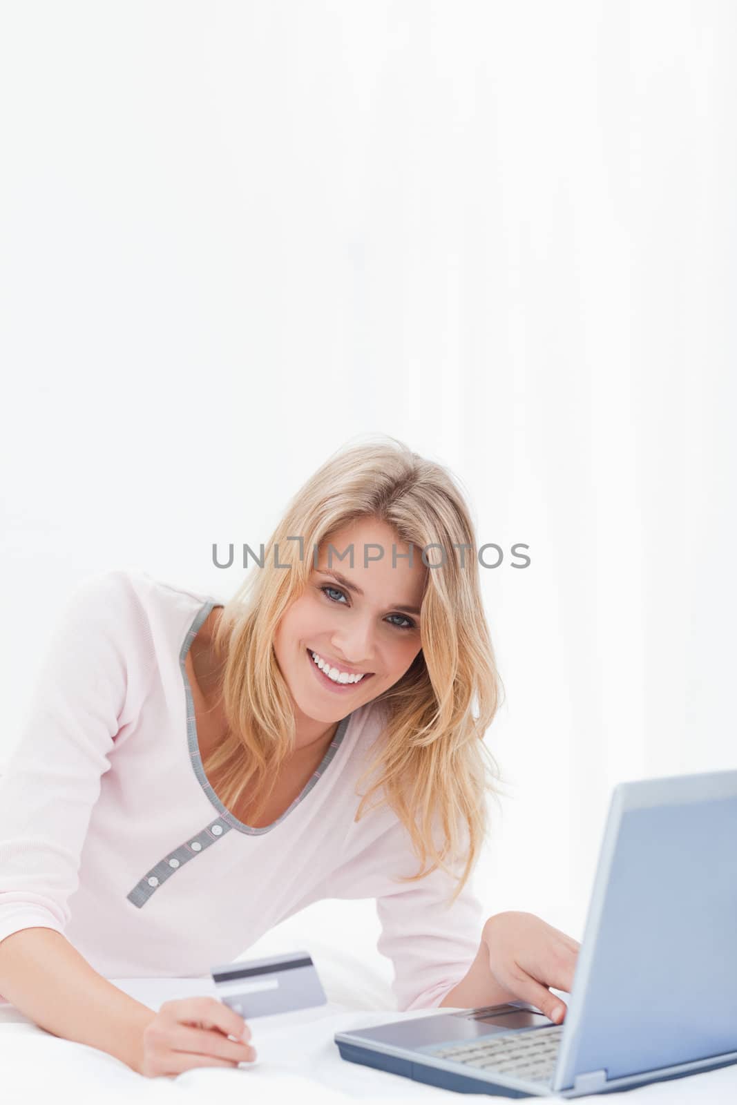 Woman using her laptop and credit card to order online. while looking forward and smiling.