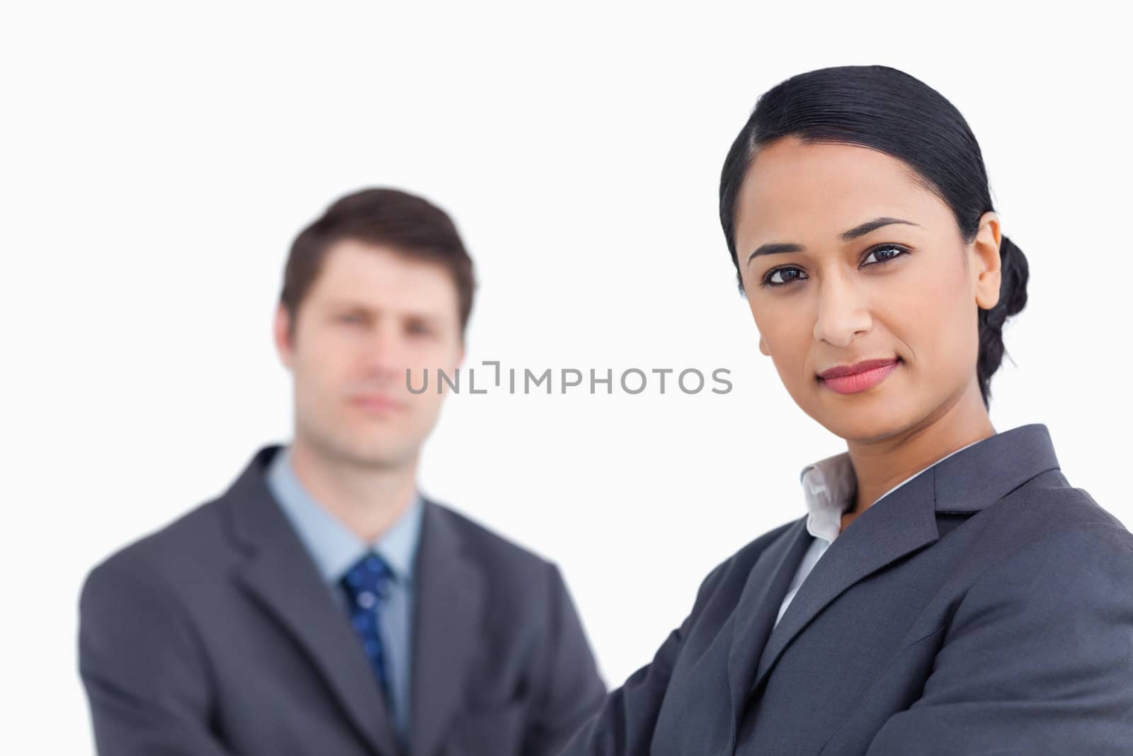 Close up of confident saleswoman with co-worker behind her against a white background
