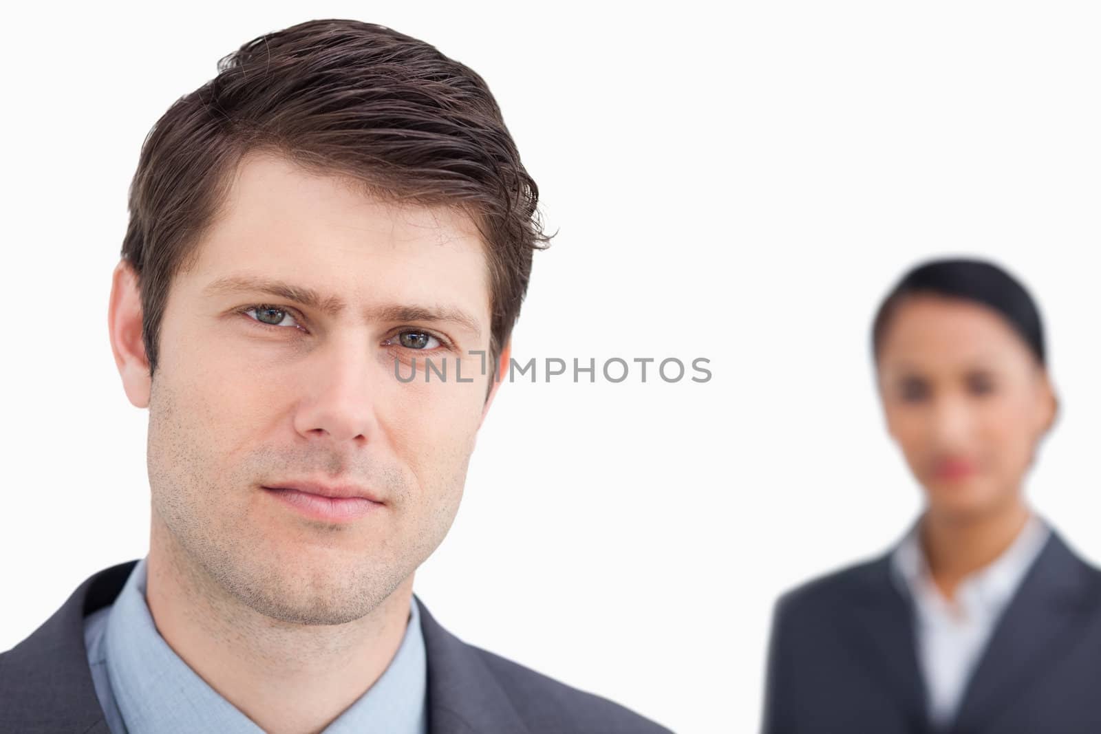 Close up of young salesman with colleague behind him against a white background