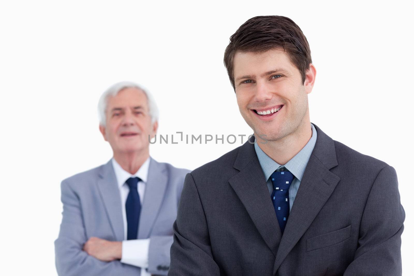 Close up of smiling businessman with his boss behind him against a white background