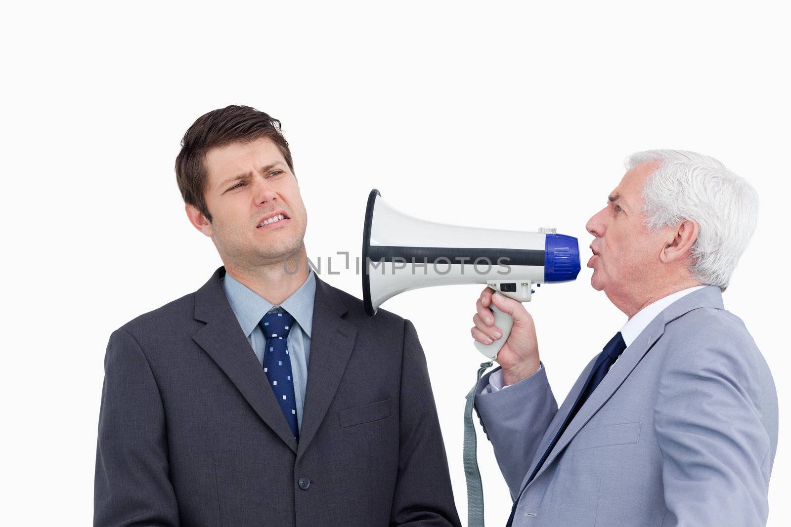 Close up of mature businessman with megaphone yelling at colleague against a white background