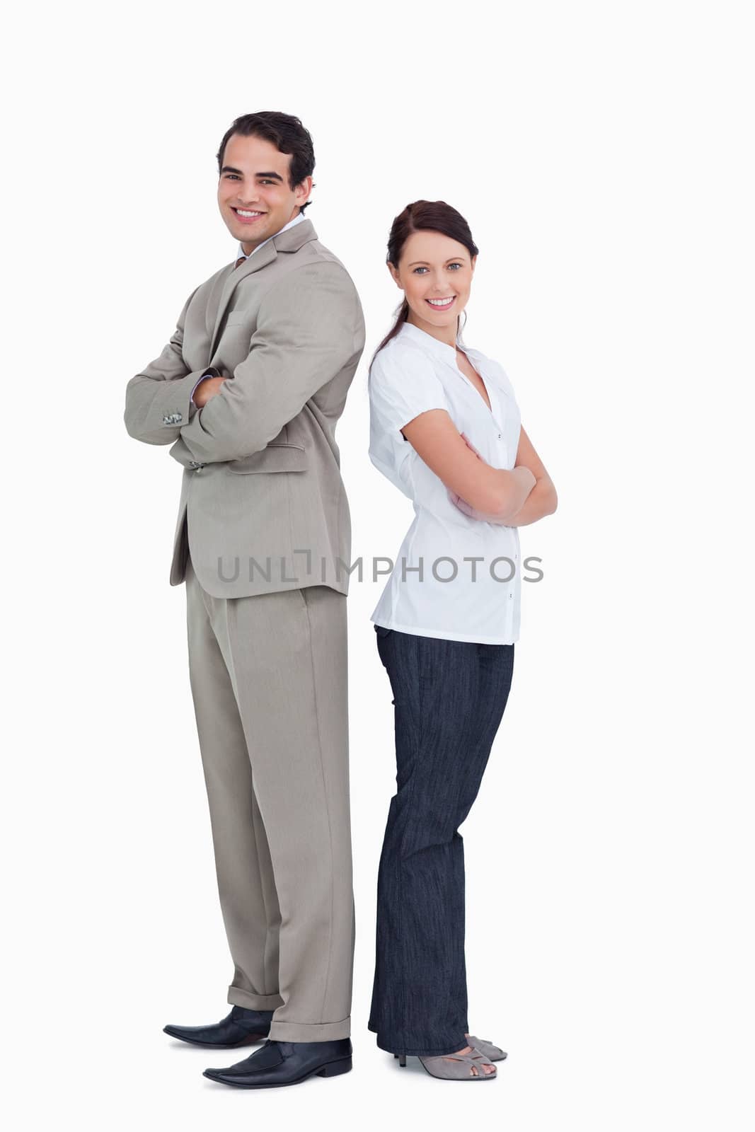 Smiling salesteam with arms folded standing back to back against a white background