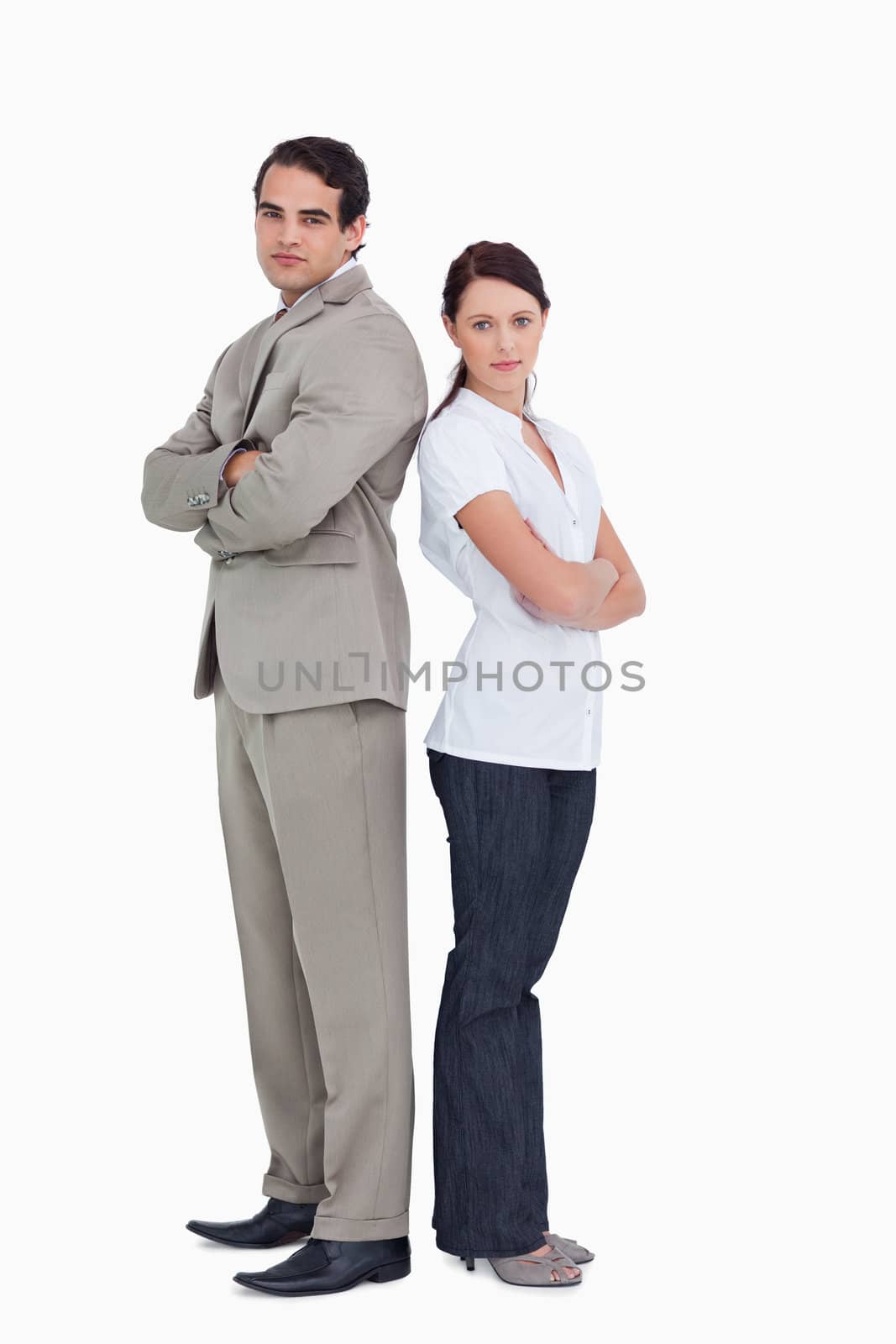 Serious salesteam with arms folded standing back to back against a white background