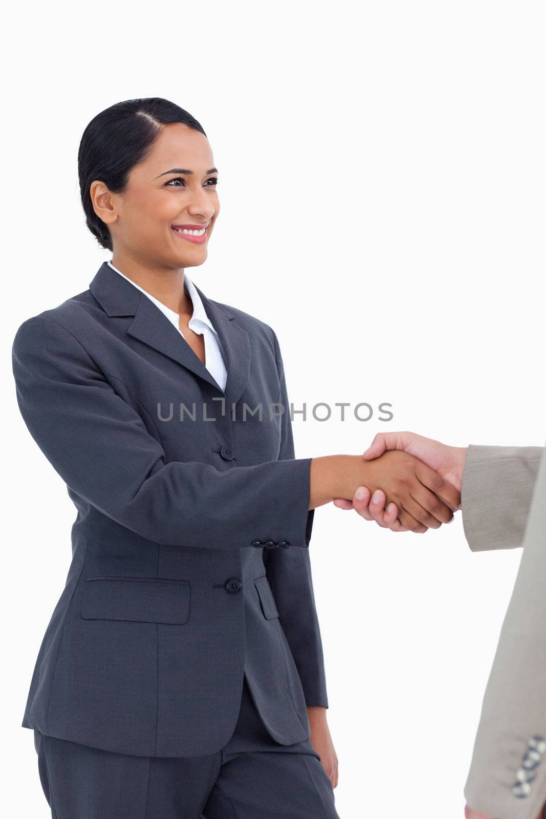 Smiling saleswoman shaking hand against a white background