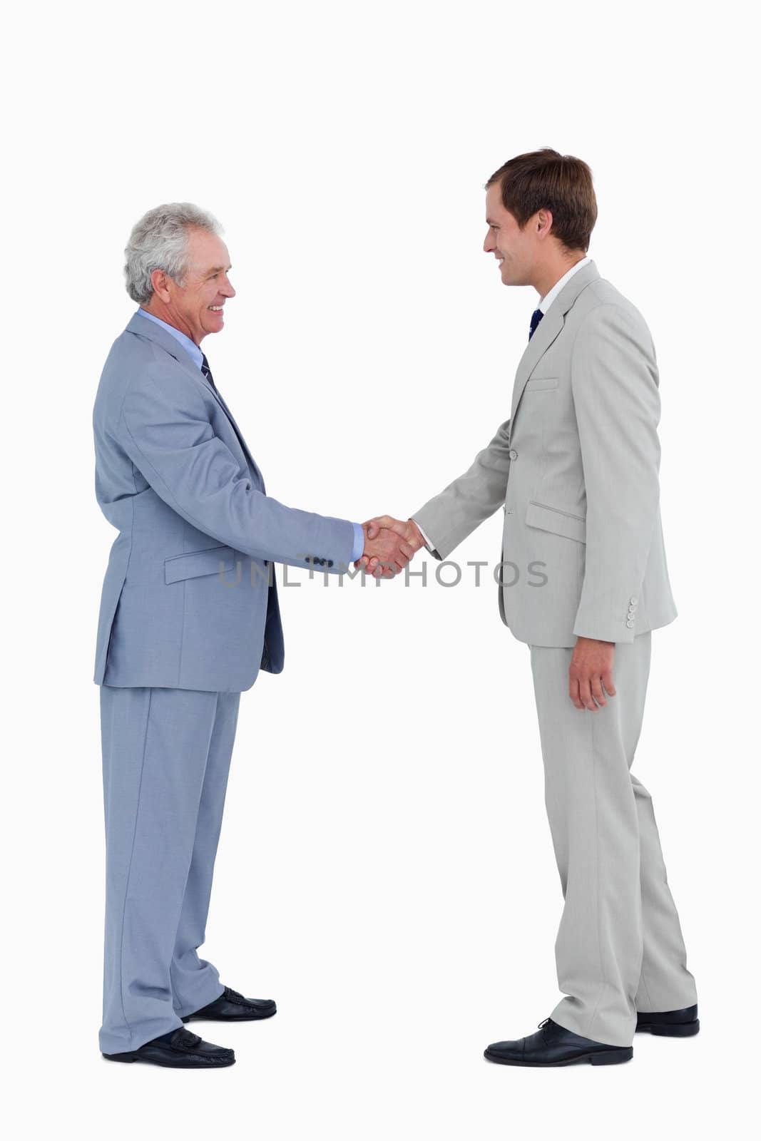 Side view of smiling tradesmen shaking hands against a white background