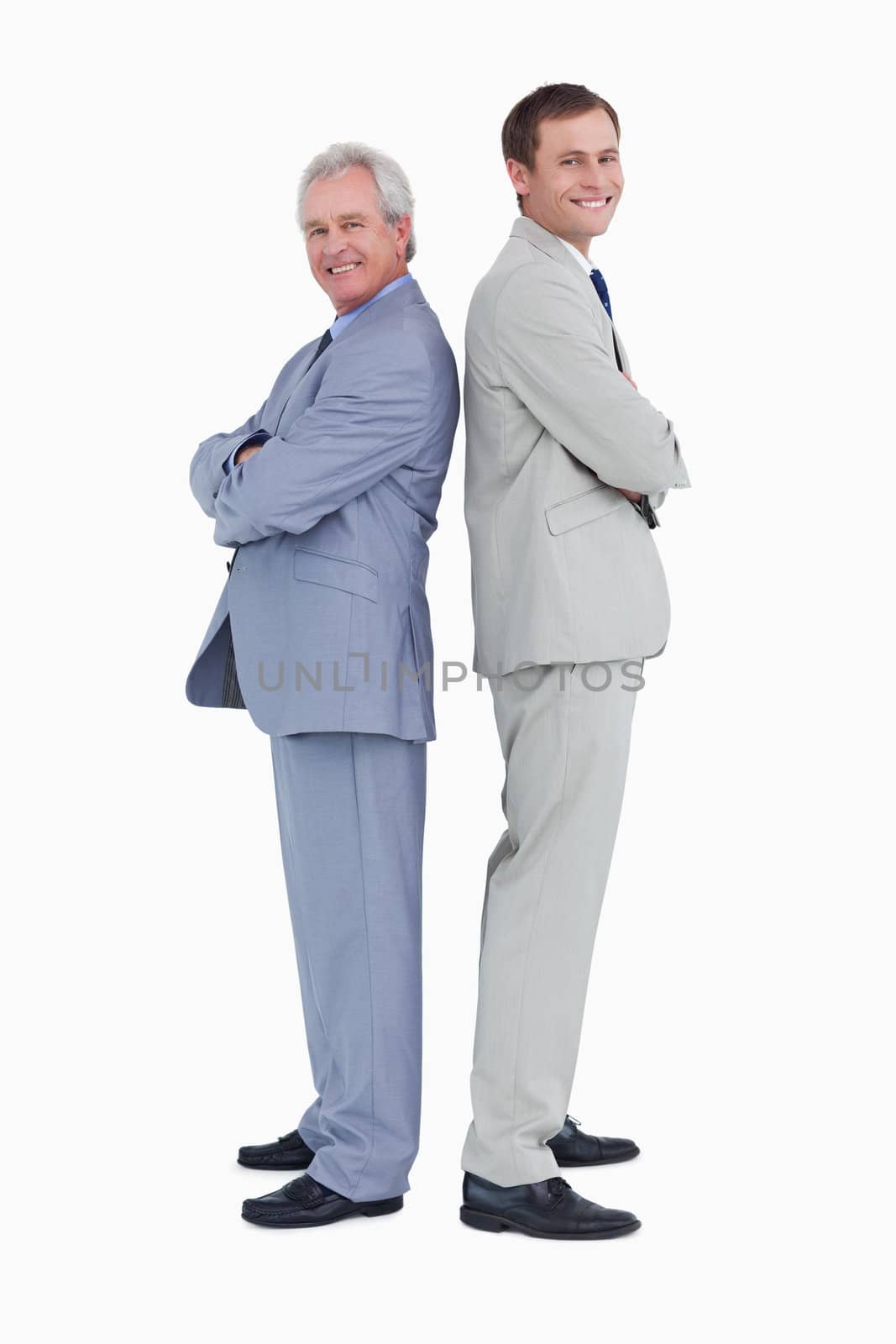 Smiling tradesmen standing back to back against a white background