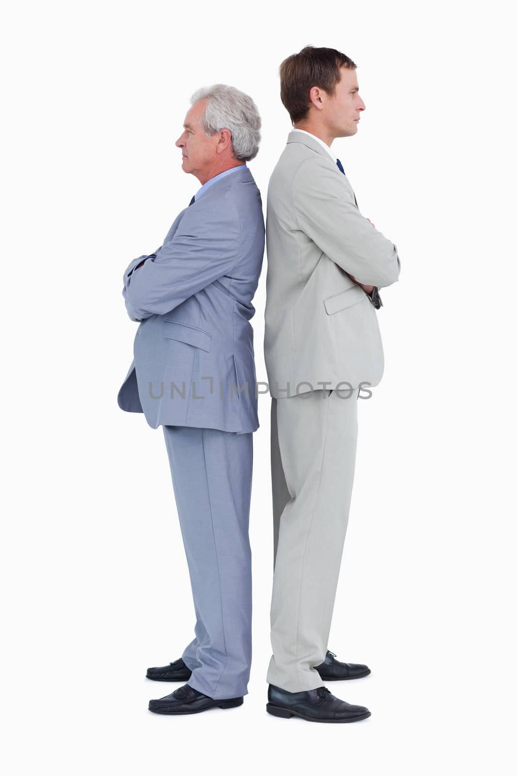 Side view of serious tradesmen standing back to back against a white background