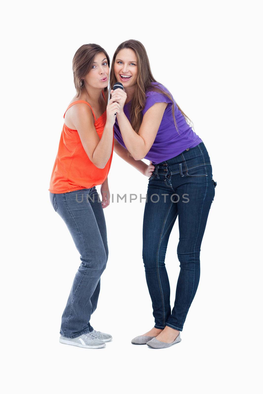 Two smiling teenagers naturally bending their bodies while singing