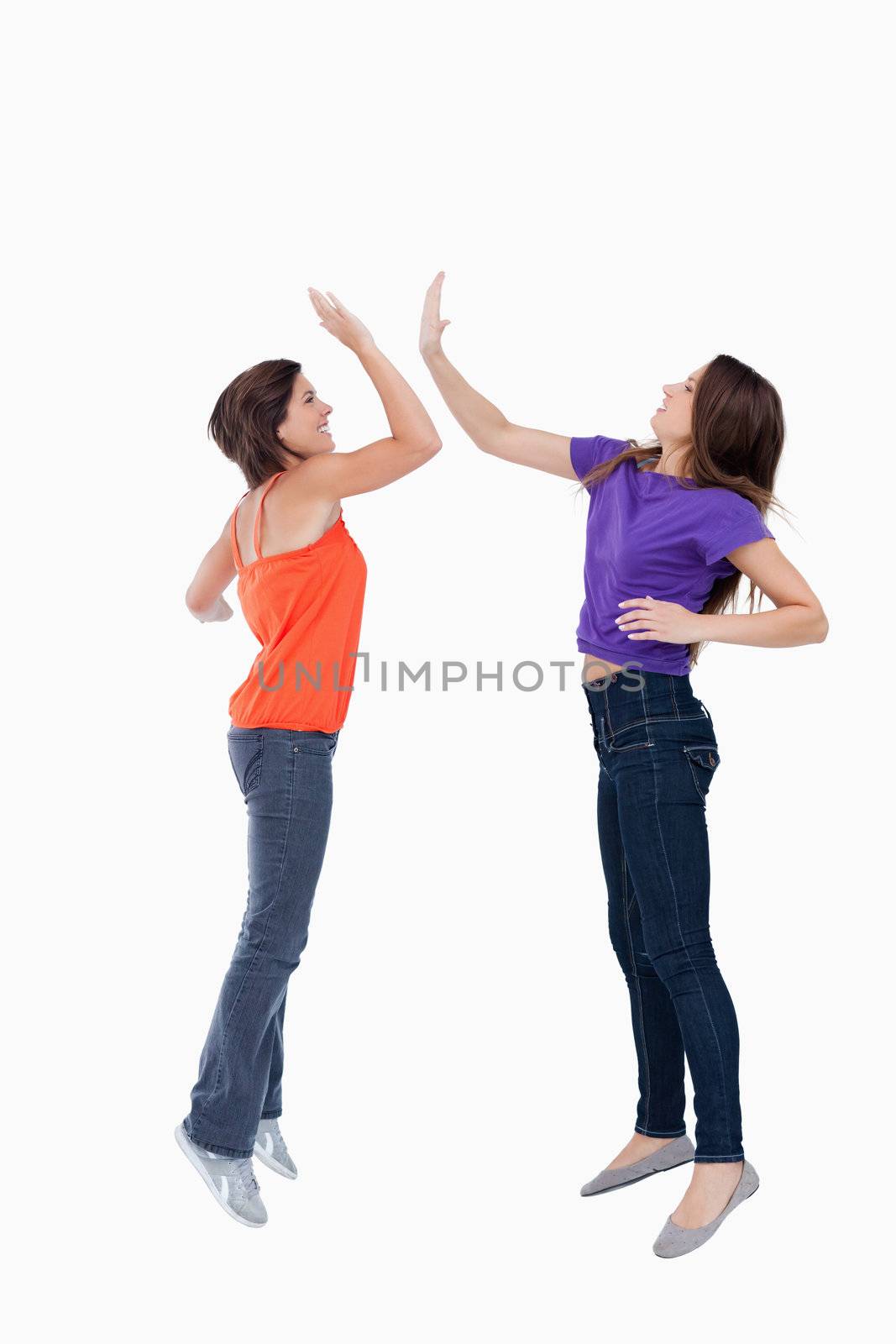 Smiling and dynamic teenagers jumping while giving a high-five