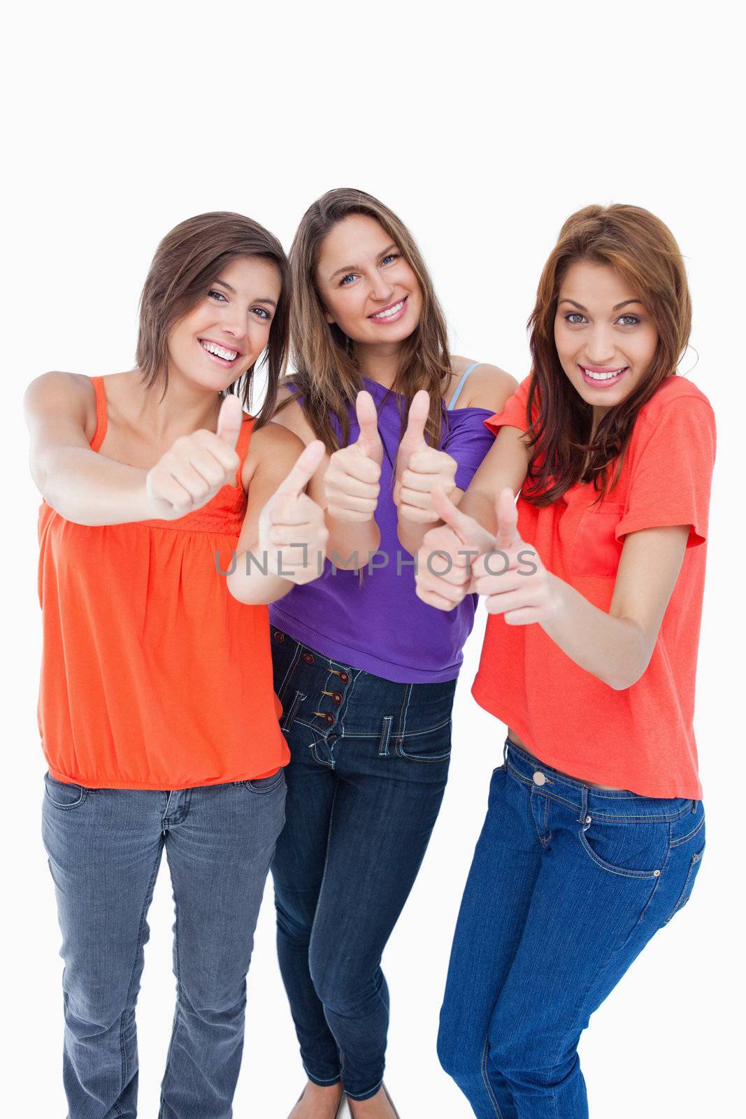 Teenage girls showing their happiness by putting their thumbs up by Wavebreakmedia