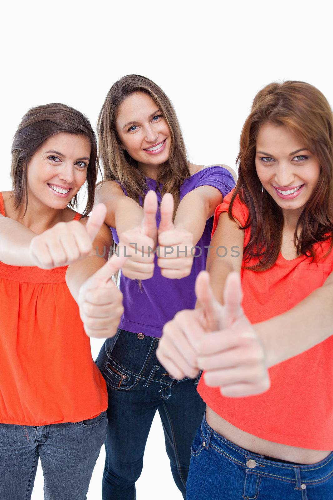 Teenagers putting their thumbs up while standing against a colourless background