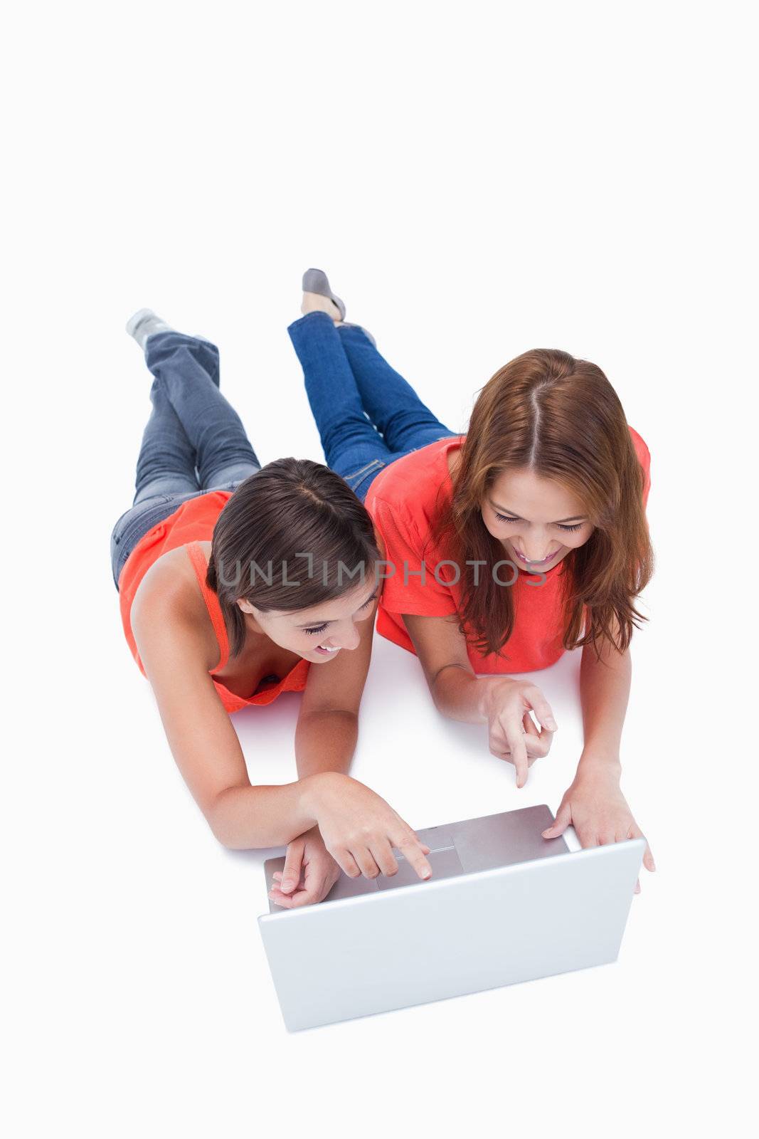 Two smiling teenagers pointing the laptop screen against a white background