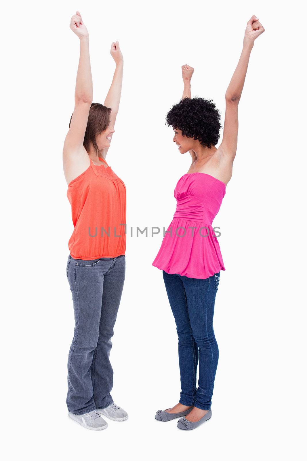 Two dynamic teenagers raising their arms in satisfaction by Wavebreakmedia