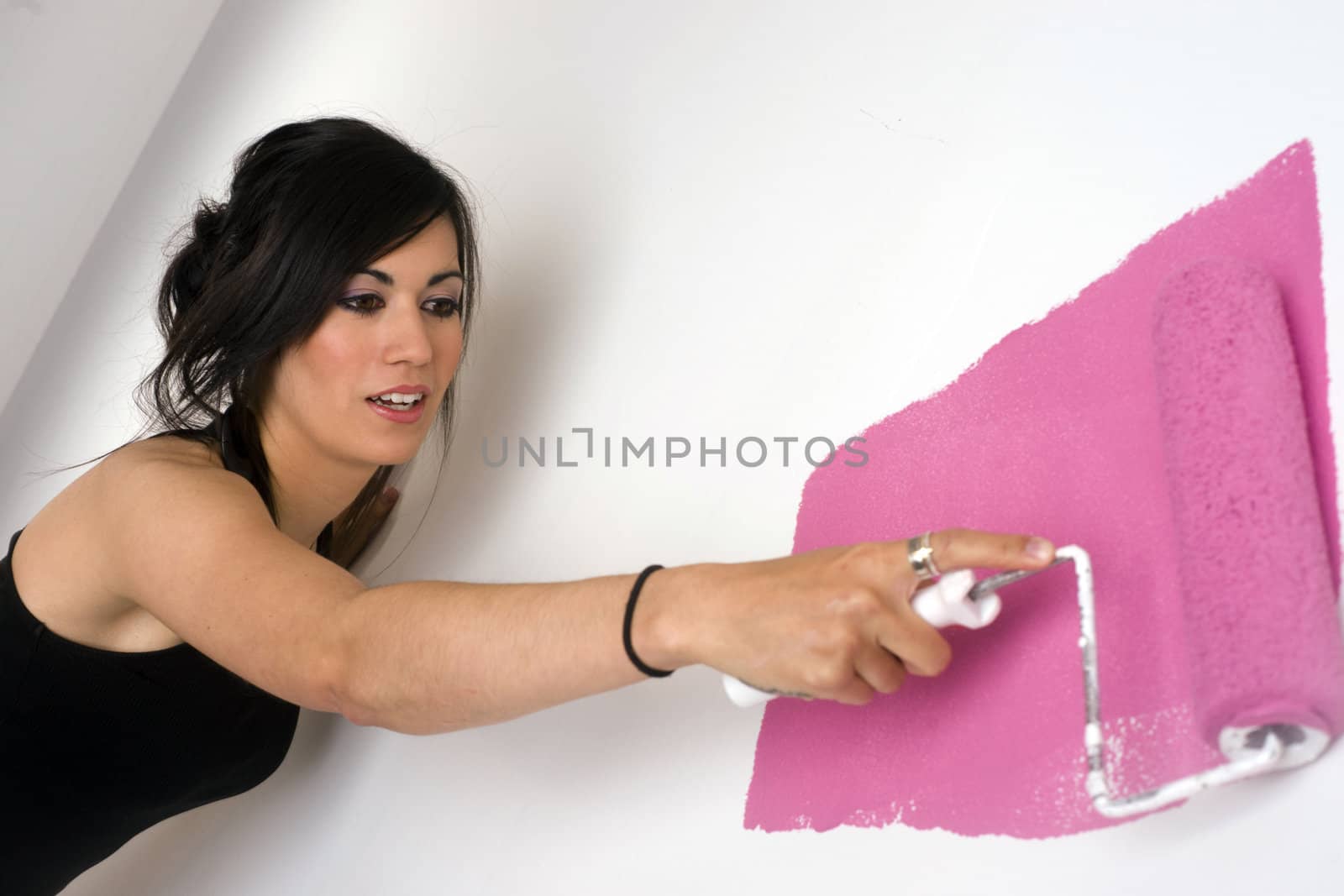 A beautiful woman paints the wall pink