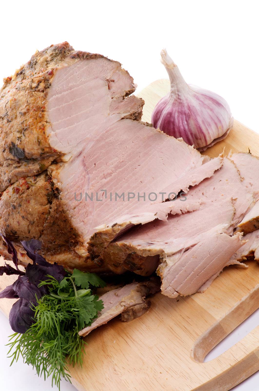 Pork Roast and Slices on Cutting Board with Greens and Garlic close up