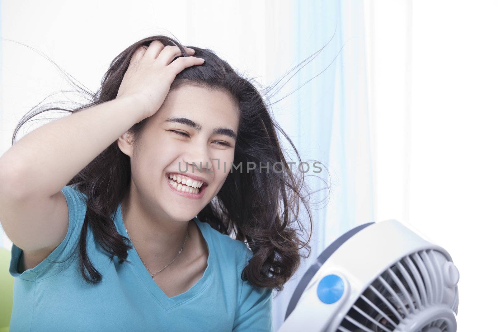 Beautiful young woman or teen enjoying cool fan breeze