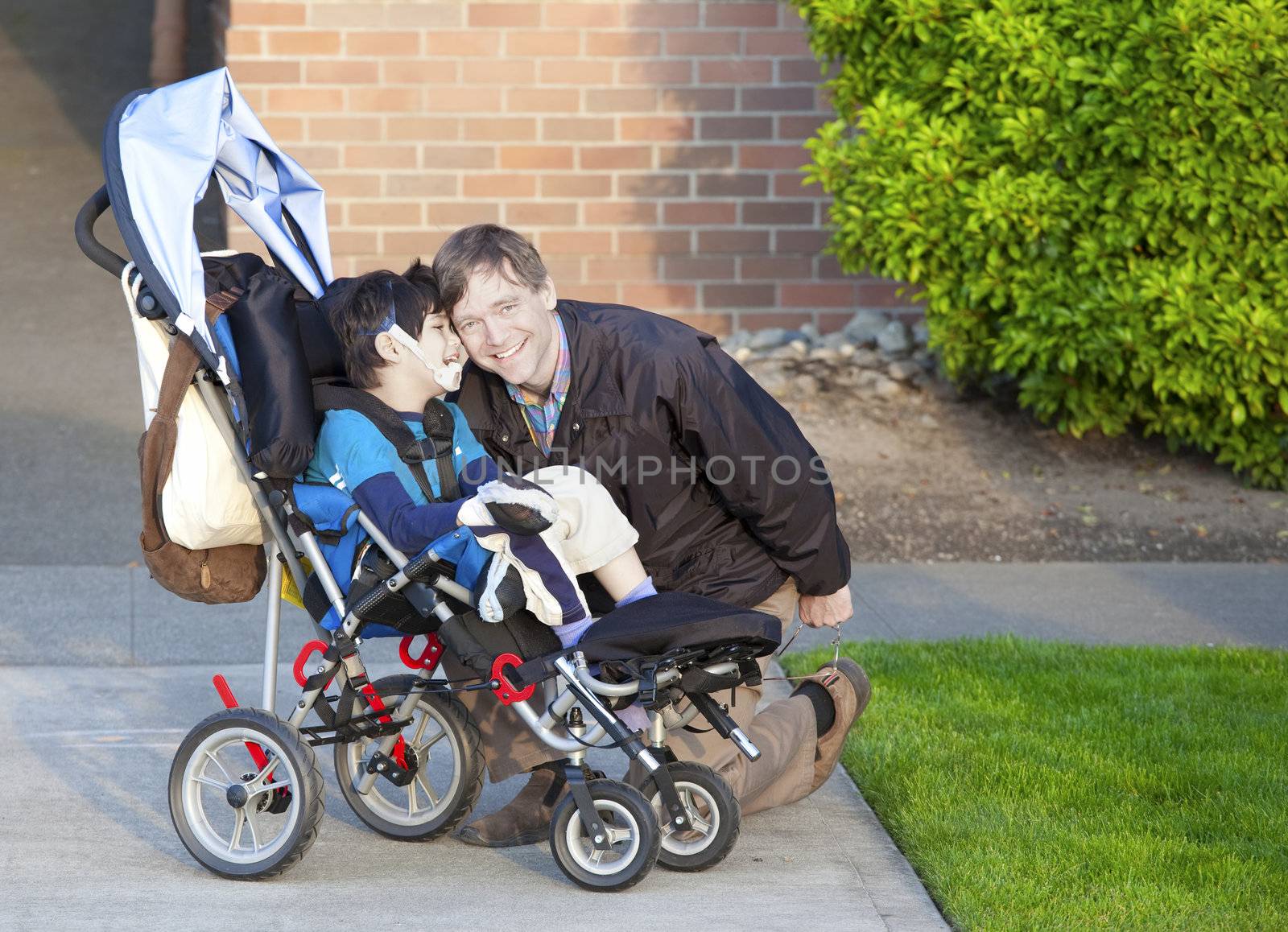 Disabled boy in wheelchair and his father