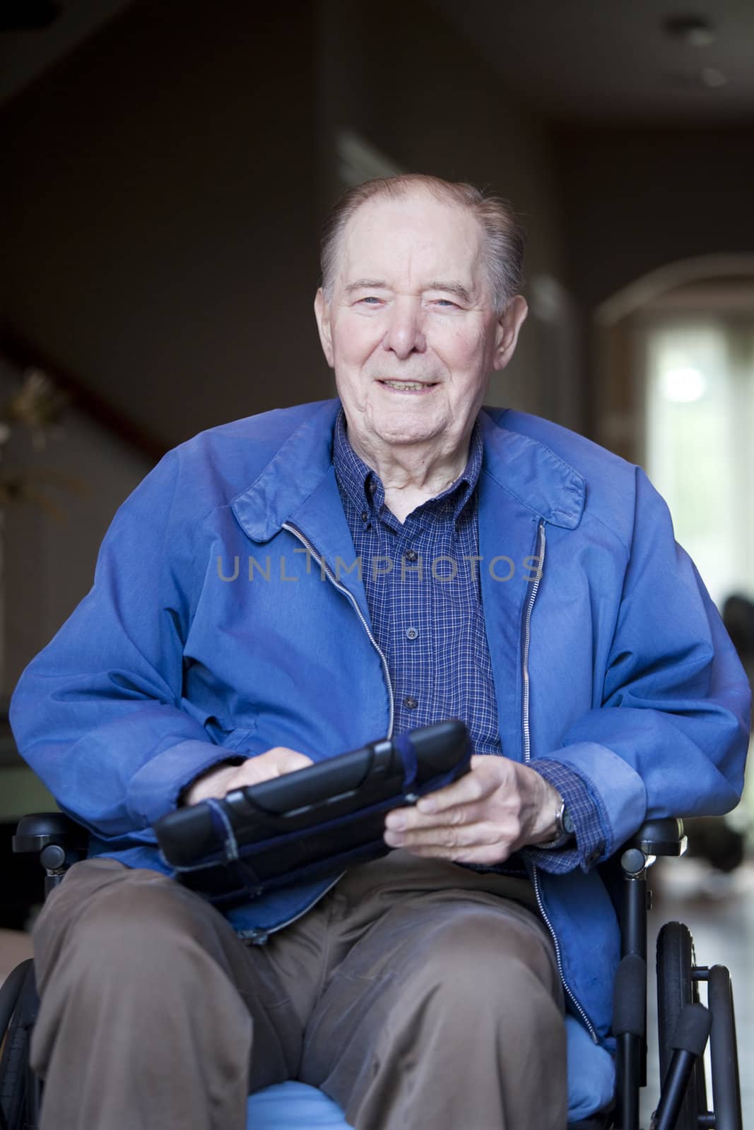 Elderly 90 yr old man in wheelchair holding tablet computer