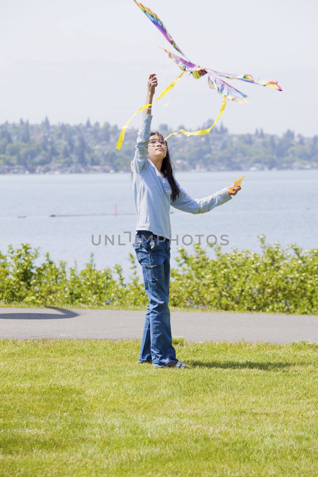 Biracial asian girl flying kite by the lake