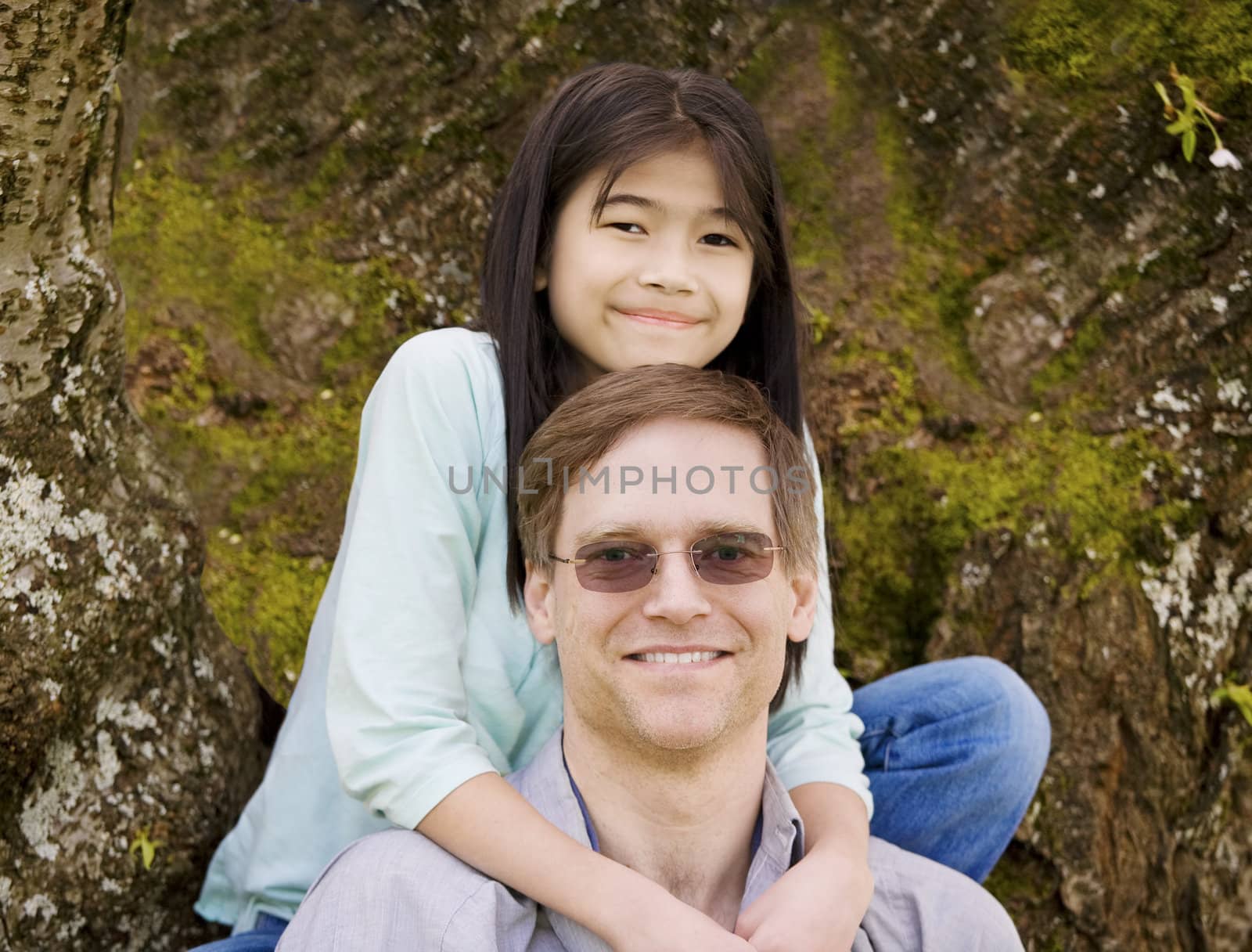 Biracial ten year old girl hugging her father around neck