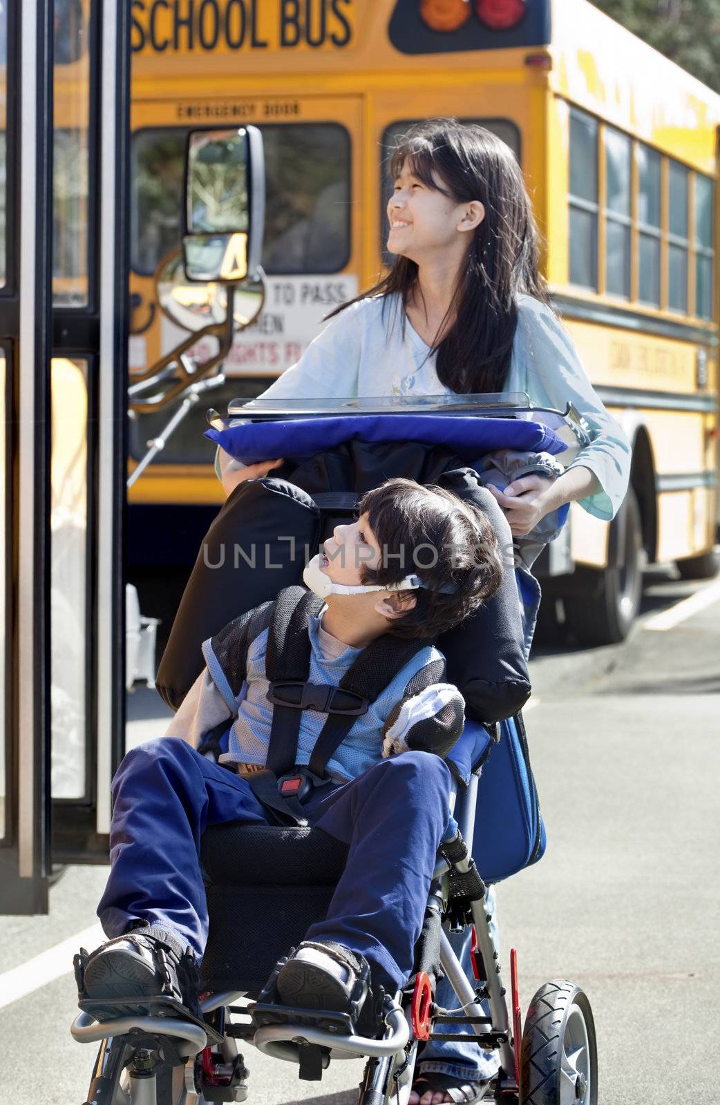 Big sister pushing disabled brother in wheelchair at school by jarenwicklund