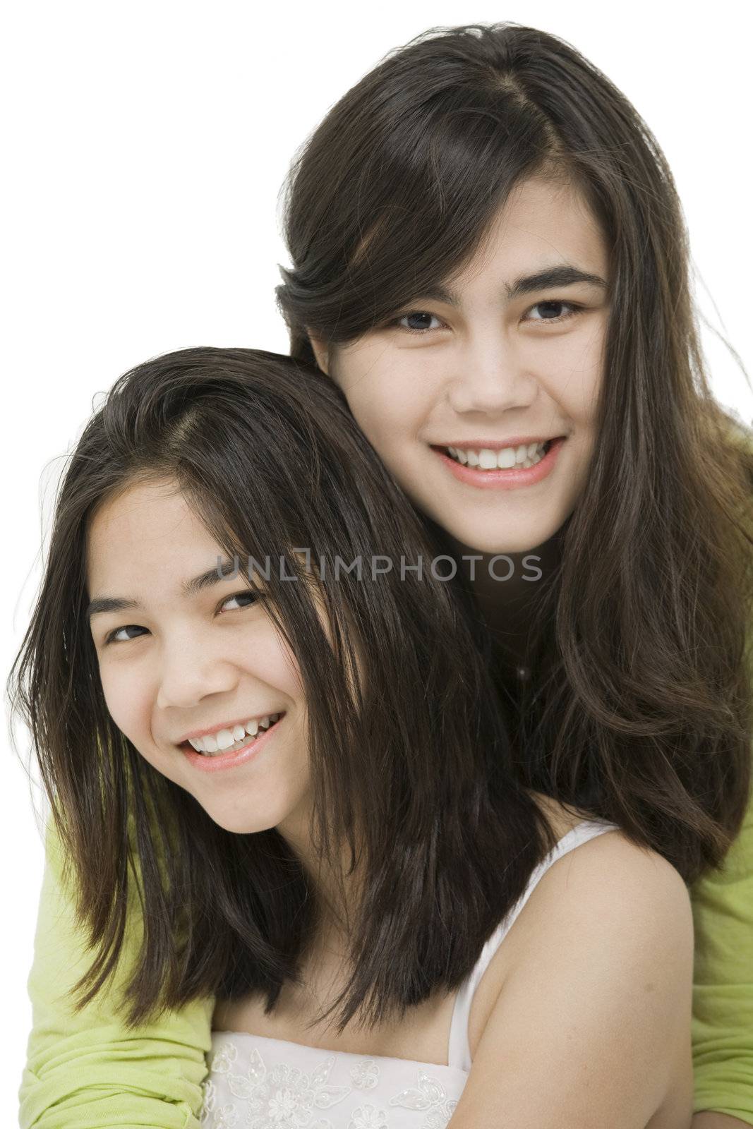 Two sisters or friends hugging each other, isolated on white